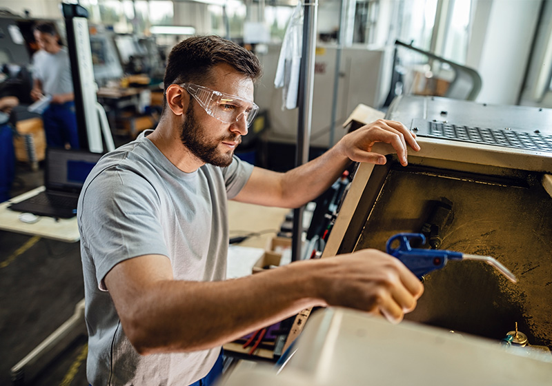 Männlicher Facharbeiter beim Montieren von Metallkomponenten mit Schutzbrille in der industriellen Fertigung. Männlicher Facharbeiter beim Montieren von Metallkomponenten mit Schutzbrille in der industriellen Fertigung.